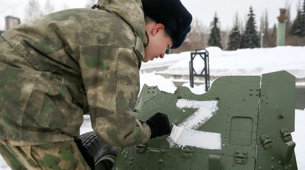 A Russian soldier paints a Z on a tank.